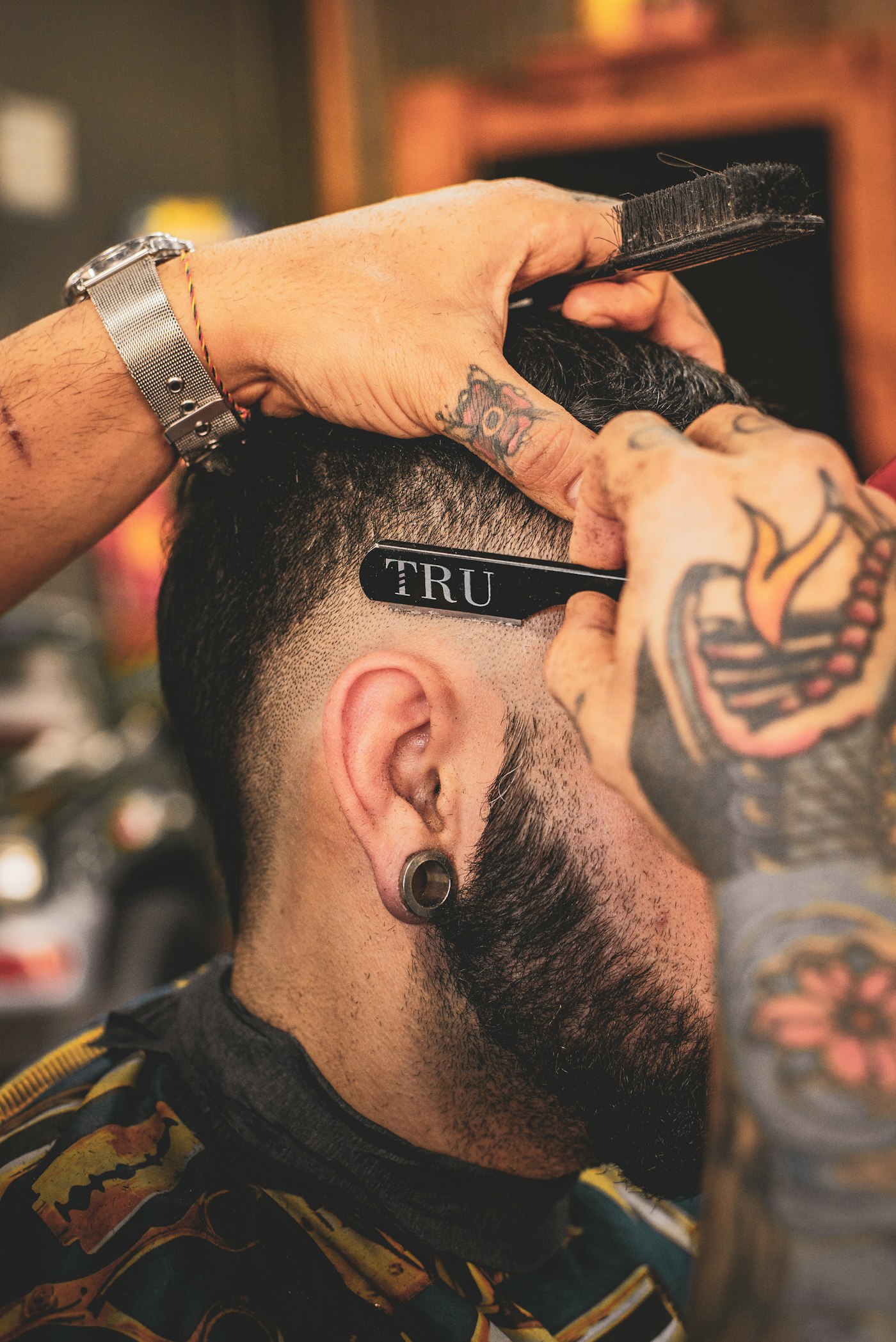 Barber finishing a fade with a straight razor, mid-cut